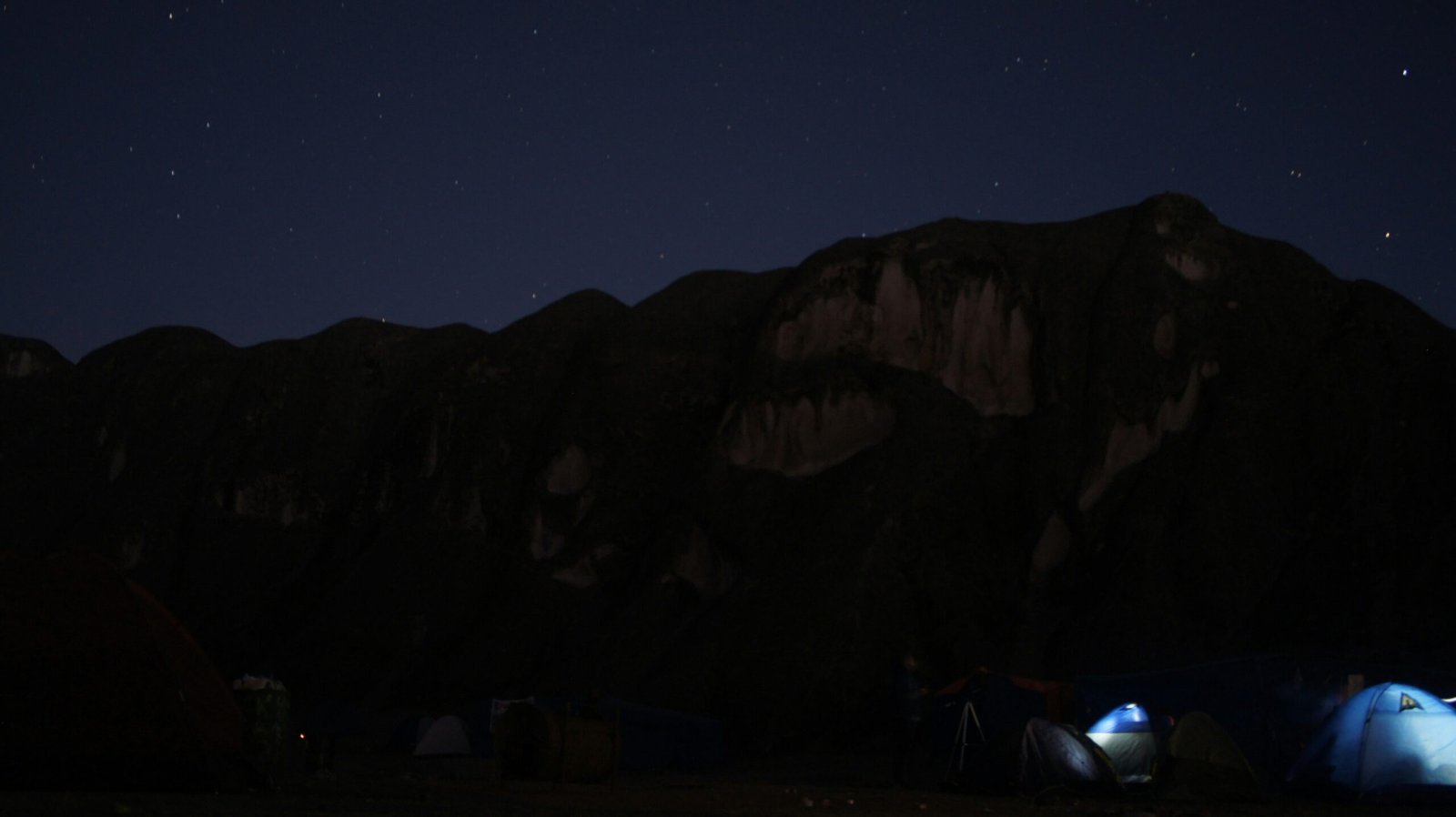 A film crew setting up lights amidst rocky terrain