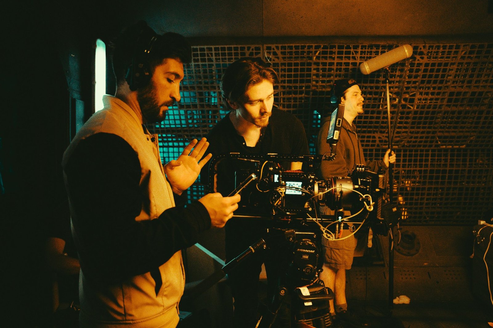 A crew member shielding camera gear from heavy rain during a shoot.